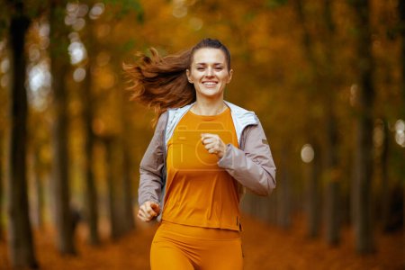Photo for Hello autumn. happy young woman in fitness clothes in the park jogging. - Royalty Free Image