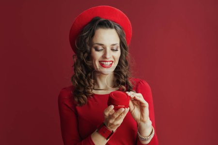 Téléchargez les photos : Joyeux Valentin. femme moderne souriante en robe rouge et béret avec boîte à bijoux isolé sur rouge. - en image libre de droit