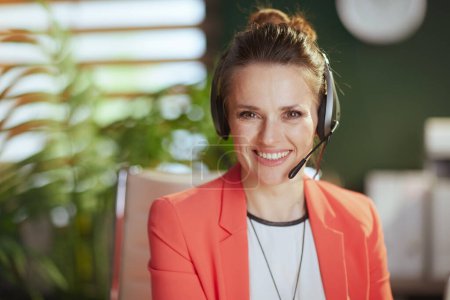 Photo for Sustainable workplace. Portrait of smiling modern business woman at work in a red jacket with headset. - Royalty Free Image