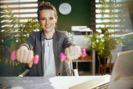 Photo for Sustainable workplace. happy modern small business owner woman at work with dumbbells. - Royalty Free Image
