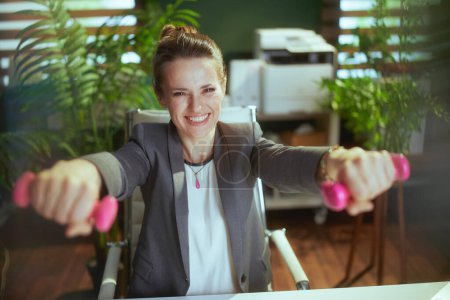 Photo for Sustainable workplace. smiling modern small business owner woman at work with dumbbells. - Royalty Free Image
