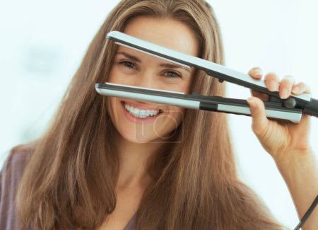 Foto de Feliz joven mujer mirando a través de plancha de pelo - Imagen libre de derechos