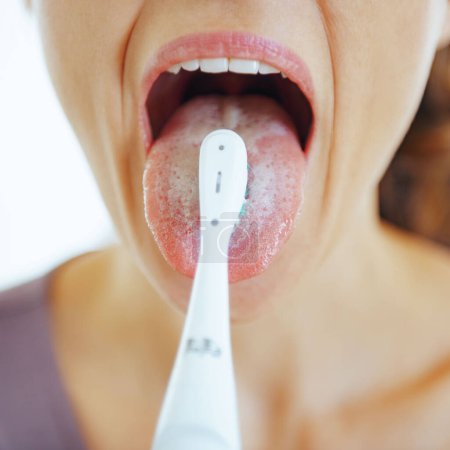 Téléchargez les photos : Gros plan sur la jeune femme nettoyage de la langue à l'aide d'une brosse à dents - en image libre de droit