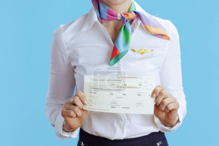 Téléchargez les photos : Gros plan sur hôtesse de l'air femme sur fond bleu en uniforme avec billets d'avion. - en image libre de droit