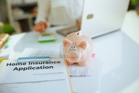 Photo for Time to move on. Closeup on woman real estate agent in green office in white blouse with piggy bank, clipboard and document. - Royalty Free Image