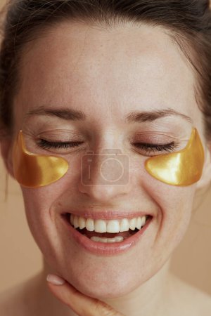 Foto de Mujer moderna feliz con parches para los ojos sobre fondo beige. - Imagen libre de derechos