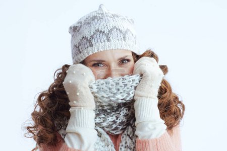 Téléchargez les photos : Bonjour l'hiver. femme à la mode en pull, mitaines, chapeau et écharpe isolé sur fond blanc enveloppant dans un foulard. - en image libre de droit