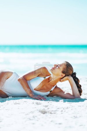 Téléchargez les photos : Jeune femme détendue allongée sur la plage - en image libre de droit