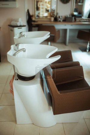 Foto de Moderno estudio de cabello con sillas y unidad de lavado posterior del salón. - Imagen libre de derechos