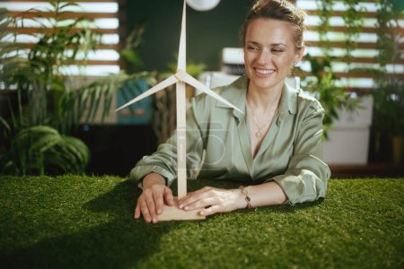 Photo for Time to go eco. happy elegant 40 years old business woman in green blouse in modern green office with windmill - Royalty Free Image