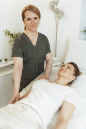Photo for Healthcare time. happy female massage therapist in massage cabinet with client conducting examination. - Royalty Free Image