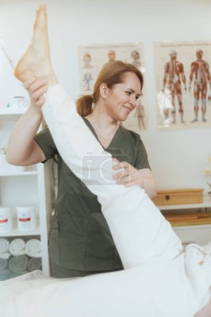 Foto de Tiempo de atención médica. terapeuta de masaje femenino sonriente en gabinete de masaje con el cliente realizando el examen. - Imagen libre de derechos