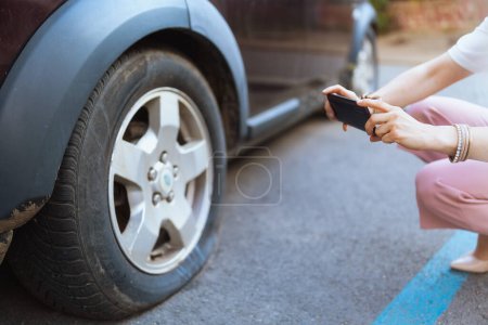 Photo for Car accident. Closeup on woman in the city with smartphone taking photo near car with flat tire. - Royalty Free Image