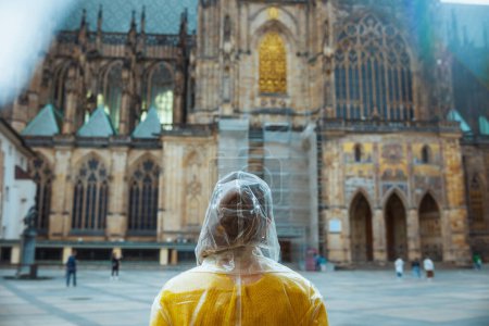 Téléchargez les photos : Vu de derrière voyageuse solitaire en chemisier jaune et imperméable à Prague République tchèque. - en image libre de droit