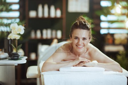 Téléchargez les photos : Temps de santé. heureux moderne femelle dans l'armoire de massage pose sur table de massage. - en image libre de droit