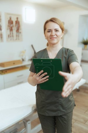 Photo for Healthcare time. happy female medical massage therapist in massage cabinet with clipboard. - Royalty Free Image