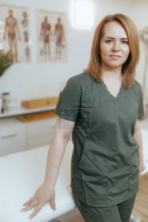 Photo for Healthcare time. pensive massage therapist woman in massage cabinet looking at camera. - Royalty Free Image