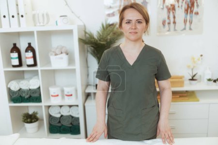 Foto de Tiempo de atención médica. sonriente masajista femenina en gabinete de masaje mirando a la cámara. - Imagen libre de derechos