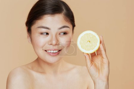 Téléchargez les photos : Moderne asiatique femme avec citron sur fond beige. - en image libre de droit