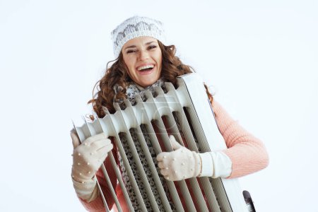 Photo for Hello winter. happy stylish middle aged woman in sweater, mittens, hat and scarf with heater isolated on white. - Royalty Free Image