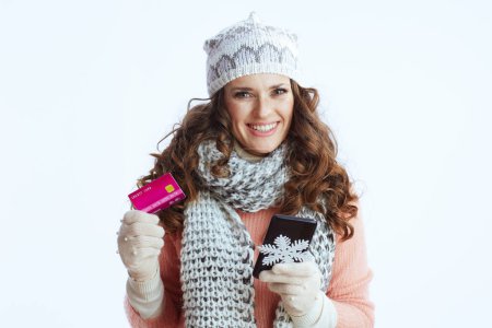 Téléchargez les photos : Bonjour l'hiver. femme moderne heureuse en pull, mitaines, chapeau et écharpe avec flocon de neige, smartphone et carte de crédit faire des achats en ligne sur le site e-commerce isolé sur blanc. - en image libre de droit