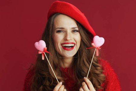 Photo for Happy Valentine. happy elegant 40 years old woman in red sweater and beret with hearts on stick. - Royalty Free Image