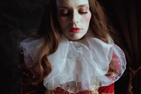 Foto de Reina medieval en vestido rojo con cuello blanco sobre fondo gris oscuro. - Imagen libre de derechos