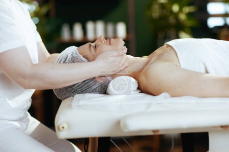 Foto de Tiempo de atención médica. terapeuta de masaje médico en el salón de spa masajear a los clientes cara en la mesa de masaje. - Imagen libre de derechos
