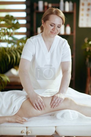Téléchargez les photos : Temps de santé. massothérapeute médical dans le salon de spa masser les clients jambe sur table de massage. - en image libre de droit