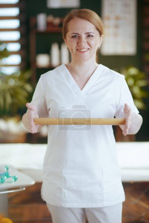 Téléchargez les photos : Temps de santé. heureuse massothérapeute femme dans armoire de massage avec bâton de massage en bois. - en image libre de droit