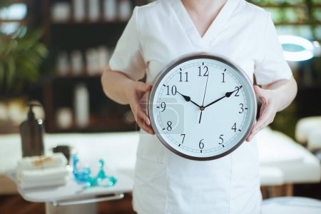 Photo for Healthcare time. Closeup on female medical massage therapist in massage cabinet with clock. - Royalty Free Image
