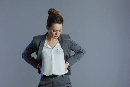 Téléchargez les photos : Souligné élégant 40 ans propriétaire de petite entreprise femme en costume gris sur fond gris. - en image libre de droit