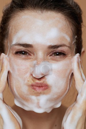 Foto de Sonriente joven hembra con espuma facial limpiador lavado de la cara. - Imagen libre de derechos