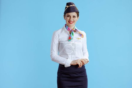 Foto de Sonriente azafata femenina moderna sobre fondo azul en uniforme. - Imagen libre de derechos