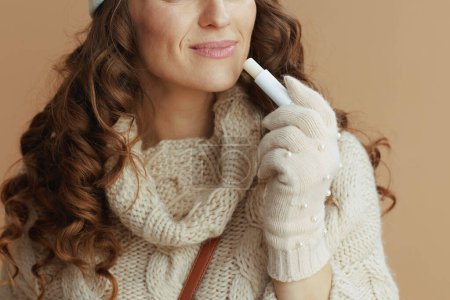 Photo for Hello winter. Closeup on woman in beige sweater, mittens and hat isolated on beige background with hygienic lipstick. - Royalty Free Image
