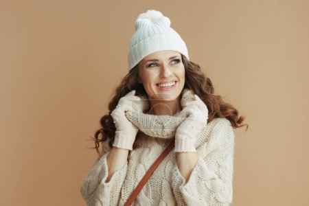 Foto de Hola invierno. Retrato de mujer moderna feliz en suéter beige, mitones y sombrero aislado en beige. - Imagen libre de derechos