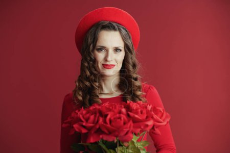 Foto de Feliz San Valentín. moderna hembra en vestido rojo y boina sobre fondo rojo con rosas rojas. - Imagen libre de derechos