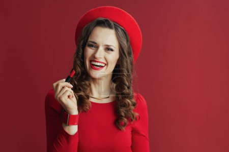 Foto de Feliz San Valentín. feliz elegante mujer de 40 años en vestido rojo y boina contra fondo rojo con lápiz labial rojo. - Imagen libre de derechos