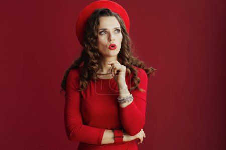 Téléchargez les photos : Joyeux Valentin. femme élégante surprise avec de longs cheveux ondulés en robe rouge et béret sur fond rouge. - en image libre de droit