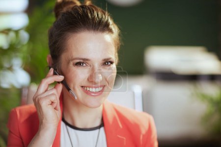 Photo for Sustainable workplace. Portrait of smiling modern small business owner woman at work in a red jacket with headset. - Royalty Free Image