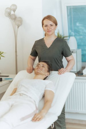 Téléchargez les photos : Temps de santé. heureuse massothérapeute femme dans armoire de massage avec client. - en image libre de droit