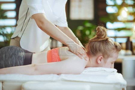 Photo for Healthcare time. female massage therapist in massage cabinet with teenage client making massage. - Royalty Free Image