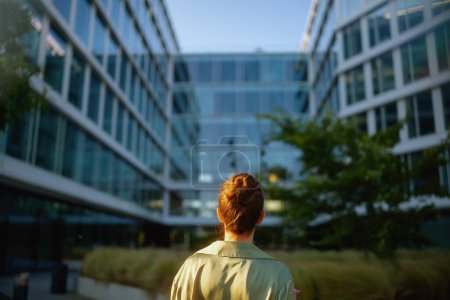 Téléchargez les photos : Vu de derrière une travailleuse près d'un immeuble de bureaux en chemisier vert. - en image libre de droit