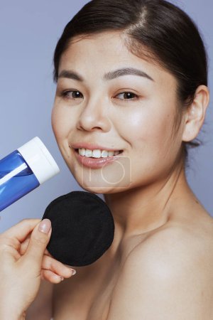 Téléchargez les photos : Portrait de femme asiatique moderne avec démaquillant et coton noir sur fond bleu. - en image libre de droit