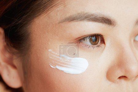 Téléchargez les photos : Gros plan sur femme asiatique avec crème pour les yeux sur le visage. - en image libre de droit