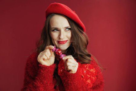 Téléchargez les photos : Joyeux Valentin. Femme souriante à la mode en pull rouge et béret avec bonbons. - en image libre de droit