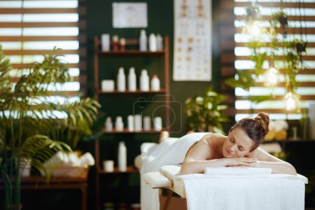 Foto de Tiempo de atención médica. relajada mujer moderna en el salón de spa acostado en la mesa de masaje. - Imagen libre de derechos