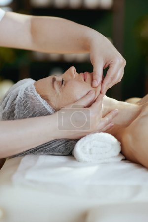 Téléchargez les photos : Temps de santé. massothérapeute médical dans l'armoire de massage massant le visage des clients sur la table de massage. - en image libre de droit