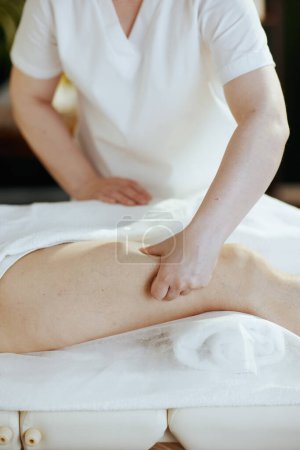 Téléchargez les photos : Temps de santé. Gros plan sur le massothérapeute médical dans l'armoire de massage massant les clients jambe sur table de massage. - en image libre de droit