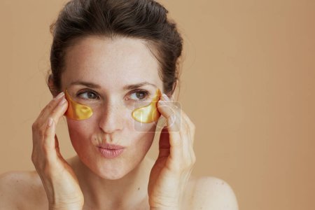 Téléchargez les photos : Femme moderne avec des patchs pour les yeux isolés sur fond beige. - en image libre de droit